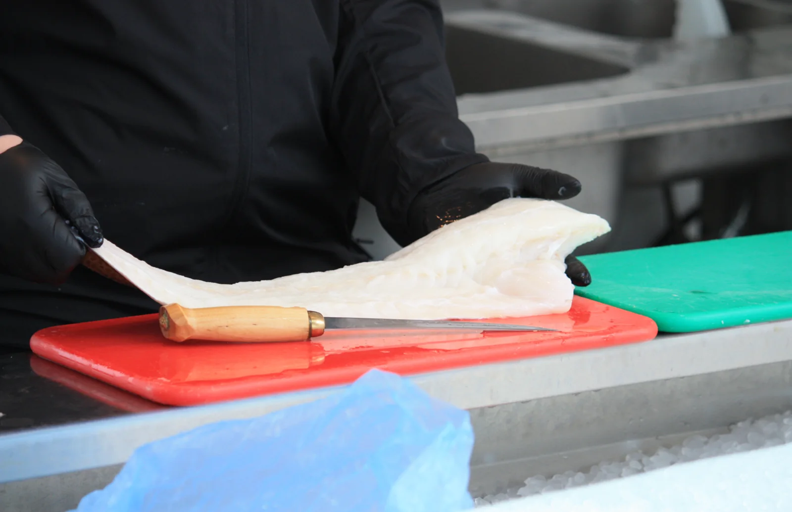 Butikksjef Sebastian skjærer loin og filet av fersk fisk i disken hos Nesttun Fisk og Vilt
